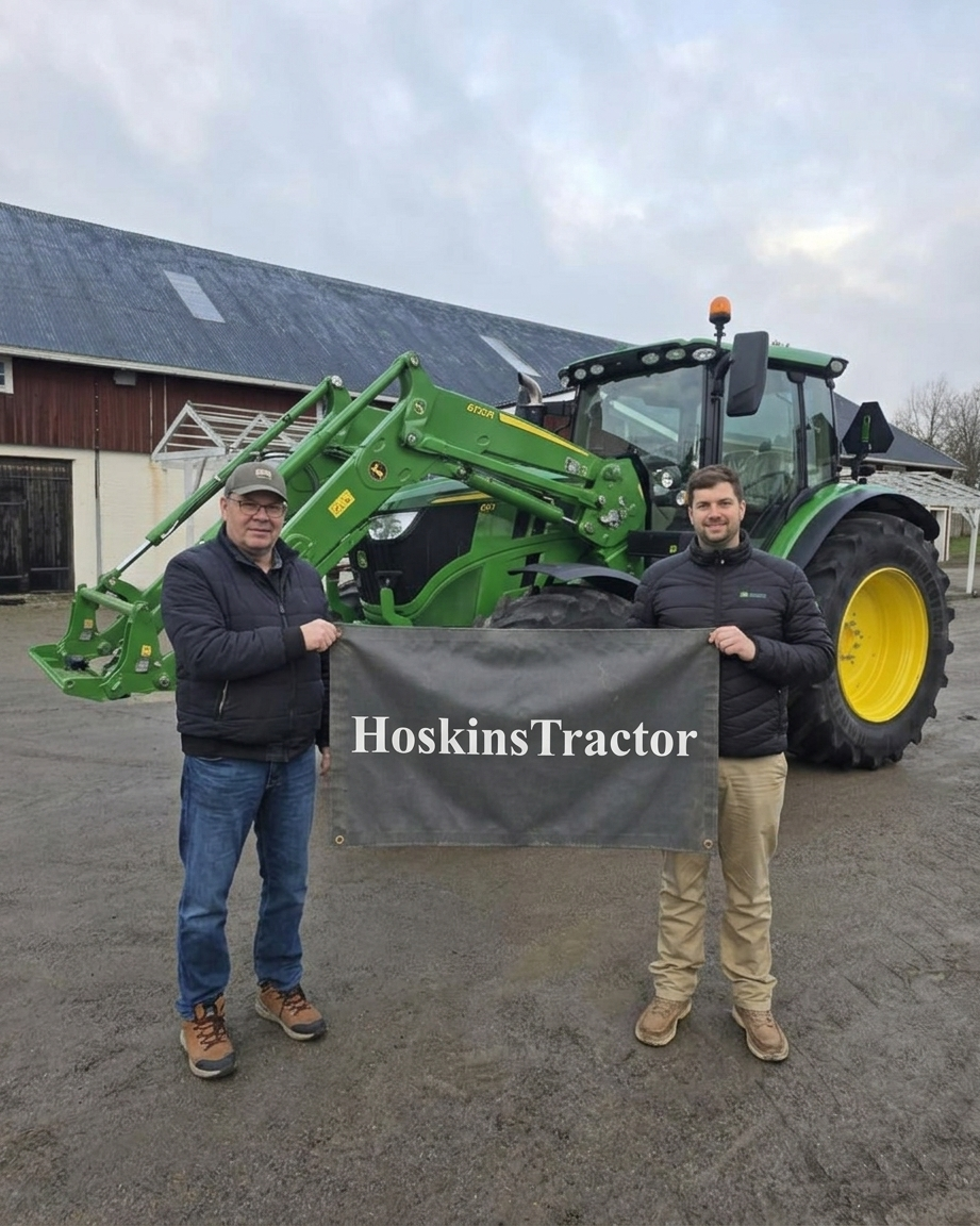 The Hoskins Auto & Tractor Sales team in front of a John Deere tractor